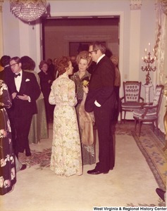 An unidentified woman speaking to an unidentified man and woman at a reception.