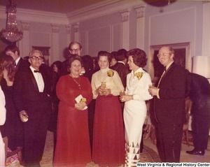 Three men and three women pose for a photo at a reception.
