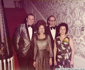 Two women and two men posing at the bottom of a stairwell for a photo at a reception.
