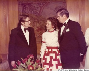 Two men and a woman having a conversation at a reception.