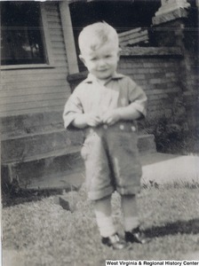 Arch Moore, Jr. standing in front of a house when he was three years old.
