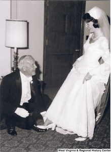 Arch Moore helping his daughter put on a shoe for her wedding to Charles Capito.