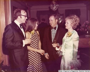 Two unidentified men and two women having a conversation at a reception.