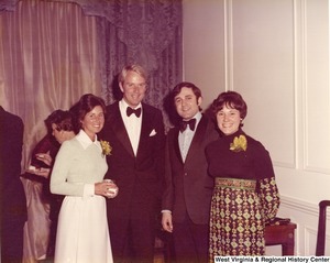 Two unidentified men and two women posing for a photo at a reception.