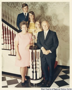 Governor Arch Moore Jr., his wife Shelley Moore, daughters Shelley Wellons and Lucy St. Clair, and son Arch A. III standing at the base of the staircase in the governors mansion.