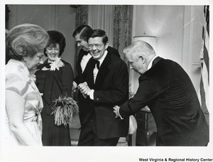 Governor Arch Moore (first on the right) with his wife Shelley (right) at a party. Three unidentified people between them are laughing.