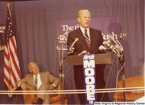 Gerald Ford speaking during Arch Moores campaign for governor. Arch Moore is seated behind Ford on the stage.