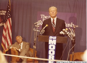 Gerald Ford speaking during Arch Moores campaign rally for governor. Arch is sitting to the left of Ford and appears to be sleeping.