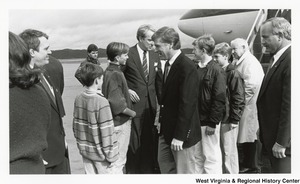 Governor Arch Moore (second from the right) with three unidentified men being greeted after disembarking from an airplane.