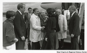 Governor Arch Moore (second from right) being greeted by his wife, Shelley, after disembarking an airplane. Three unidentified men are also greeting the passengers with Shelley.