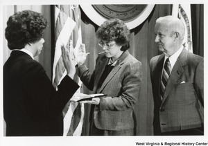 An unidentified woman is being sworn into office by another woman. Governor Arch Moore is standing with them during the ceremony.