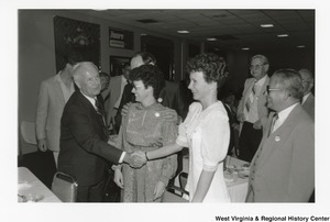 Arch Moore shaking the hand of an unidentified woman at his campaign rally for Governor. Other people are waiting to speak or shake hands with Arch.