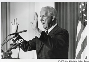 Governor Arch Moore standing with his hands in the air as he is giving a speech.