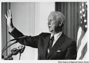Governor Arch Moore speaking at a press conference. The Governor has one hand up like he is waving to the crowd.