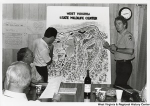 Governor Arch Moore ( lower left corner) being shown a map of the West Virginia State Wildlife Center by a member of the Department of Natural Resources (DNR).