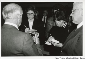 Governor Arch Moore (first on left) speaking to two unidentified women and one man. The women appear to be taking notes on the conversation.