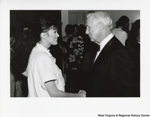 Governor Arch Moore shaking the hand of an unidentified woman at a party.