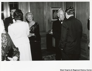 Governor Arch Moore speaking with an unidentified man at a party. Shelley Moore is speaking to an unidentified man and woman and appears to be reaching out to shake the womans hand.