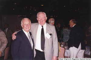 Governor Arch Moore standing with his arm around an unidentified man at a party.