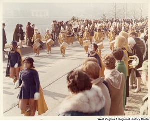 A high school marching band during Governor Arch Moores inaugural parade in Charleston. The band is wearing yellow and blue marching band uniforms.