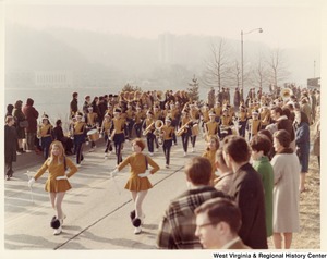 An unidentified high school marching band during Governor Arch Moores inaugural parade in Charleston. The band is wearing black and yellow uniforms. The majorettes are wearing yellow dresses with yellow hats.