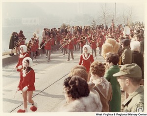 An unidentified high school during Governor Arch Moores inaugural parade in Charleston. The band is wearing red uniforms. The majorettes are wearing red dresses with white accents and white hats.